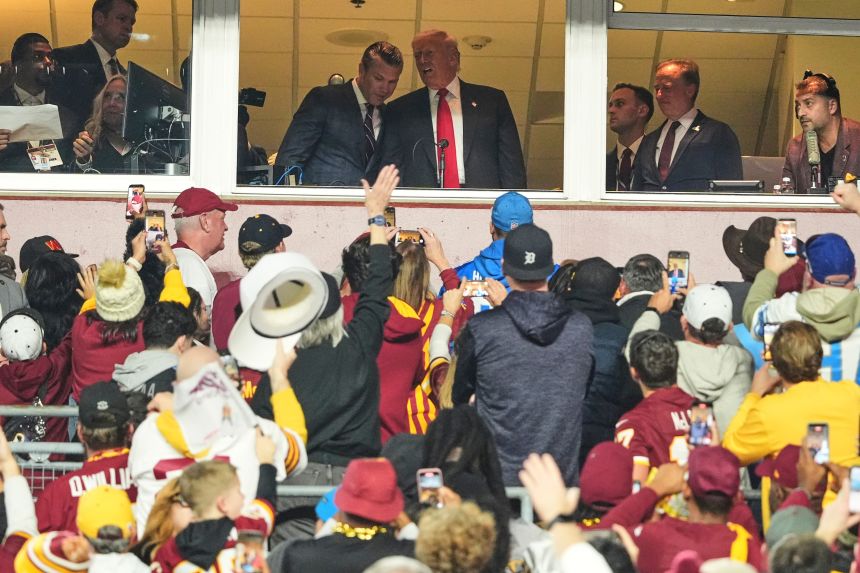 President Donald Trump talks to Defense Secretary Pete Hegseth as they attend a Washington Commanders game on Sunday.